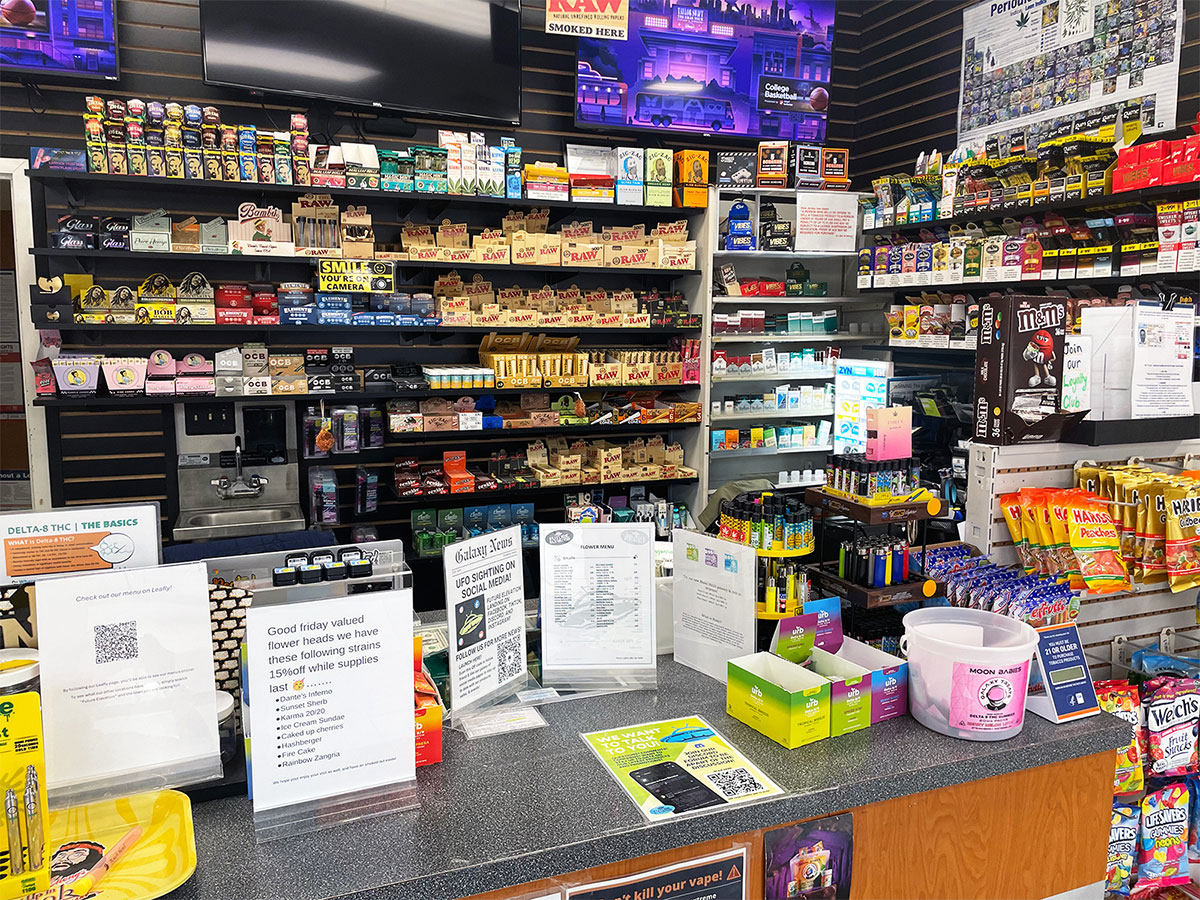A sales counter with product display behind it with rolling papers, cigarettes, and other smoking accessory products at our Shackamaxon, Scotch Plains head shop and tobacco store.