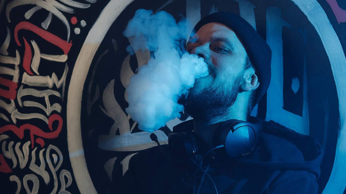 A man with sweatshirt and headphones using a THC vape near South Hackensack, New Jersey.