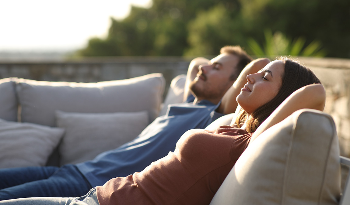 A man and woman relaxing on couches outdoors after using THC gummy cubes near San Antonio, Texas ordered online.